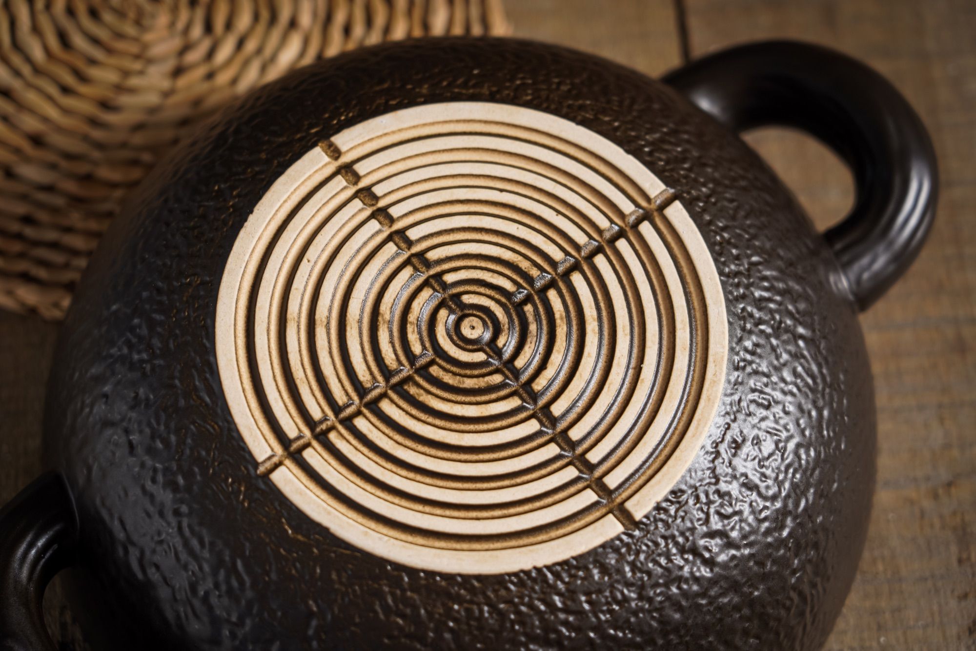 Glazed ceramic casserole standing on a woven wooden trivet.