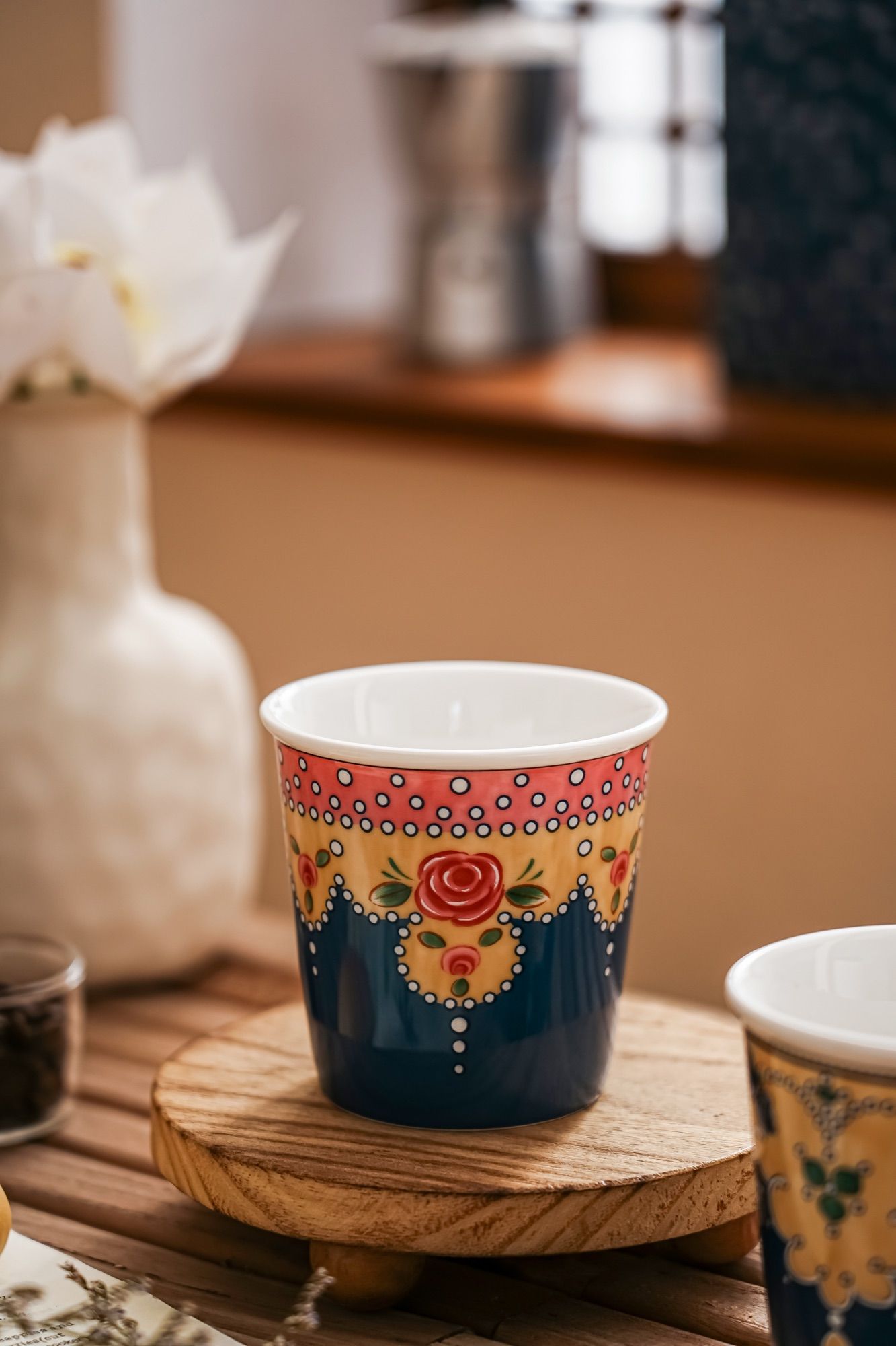 Handleless ceramic cup filled with a latte, standing on a wooden table.